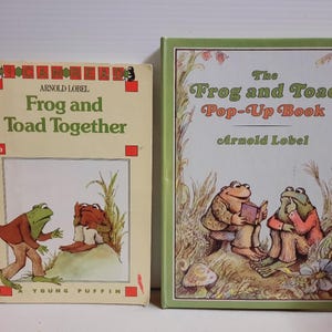 May include: Two books by Arnold Lobel: Frog and Toad Together, a cream-coloured paperback with a green title and illustration of two frogs, and The Frog and Toad Pop-Up Book, a green-bordered hardcover featuring an illustration of two frogs reading.