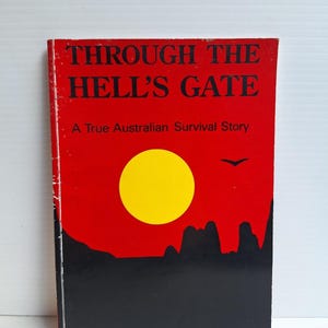 May include: A paperback book titled Through the Hell's Gate: A True Australian Survival Story. The cover features a bright red background with a large yellow sun, a black silhouette of a rocky landscape at the bottom, and a small black bird.