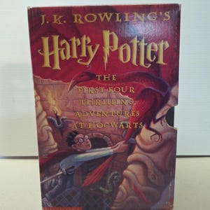 Puede incluir: Un libro de tapa dura rojo titulado "Harry Potter". La portada presenta el texto "J.K. Rowling's" y "Harry Potter" en letras doradas. La ilustración muestra una escena con un pájaro y un niño.