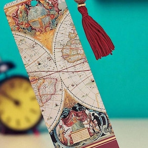 May include: A rectangular bookmark featuring a vintage world map design with a red tassel and a wooden bead. The bookmark has the quote "Wherever you go, go with all your heart." printed on it.