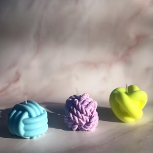 May include: A set of three ceramic mugs with a speckled, cream-colored glaze. Each mug features a different hand-painted design: a blue and green leaf, a yellow flower, and a red berry. The mugs have a simple, modern design.