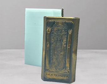 May include: A rectangular candle with a detailed image of the High Priestess tarot card. The candle has a bronze-colored front with the card's artwork and text. A light blue rectangular mold is behind the candle.