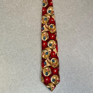 May include: A red necktie featuring a repeating pattern of circular gold-toned medallions. Each medallion contains a small cluster of blue flowers and a red ribbon detail. The background is a deep red color with small, solid red circular accents.