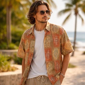 May include: A patterned short-sleeved shirt in orange, brown, and green, worn over a white t-shirt. The shirt features a paisley design. The outfit is completed with khaki trousers. The background shows palm trees and a beach.