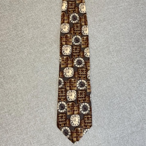 May include: A brown necktie with a repeating pattern of clocks and buildings. The clocks have white faces and black hands, set against a backdrop of brown and tan buildings. The tie is made of a smooth fabric.