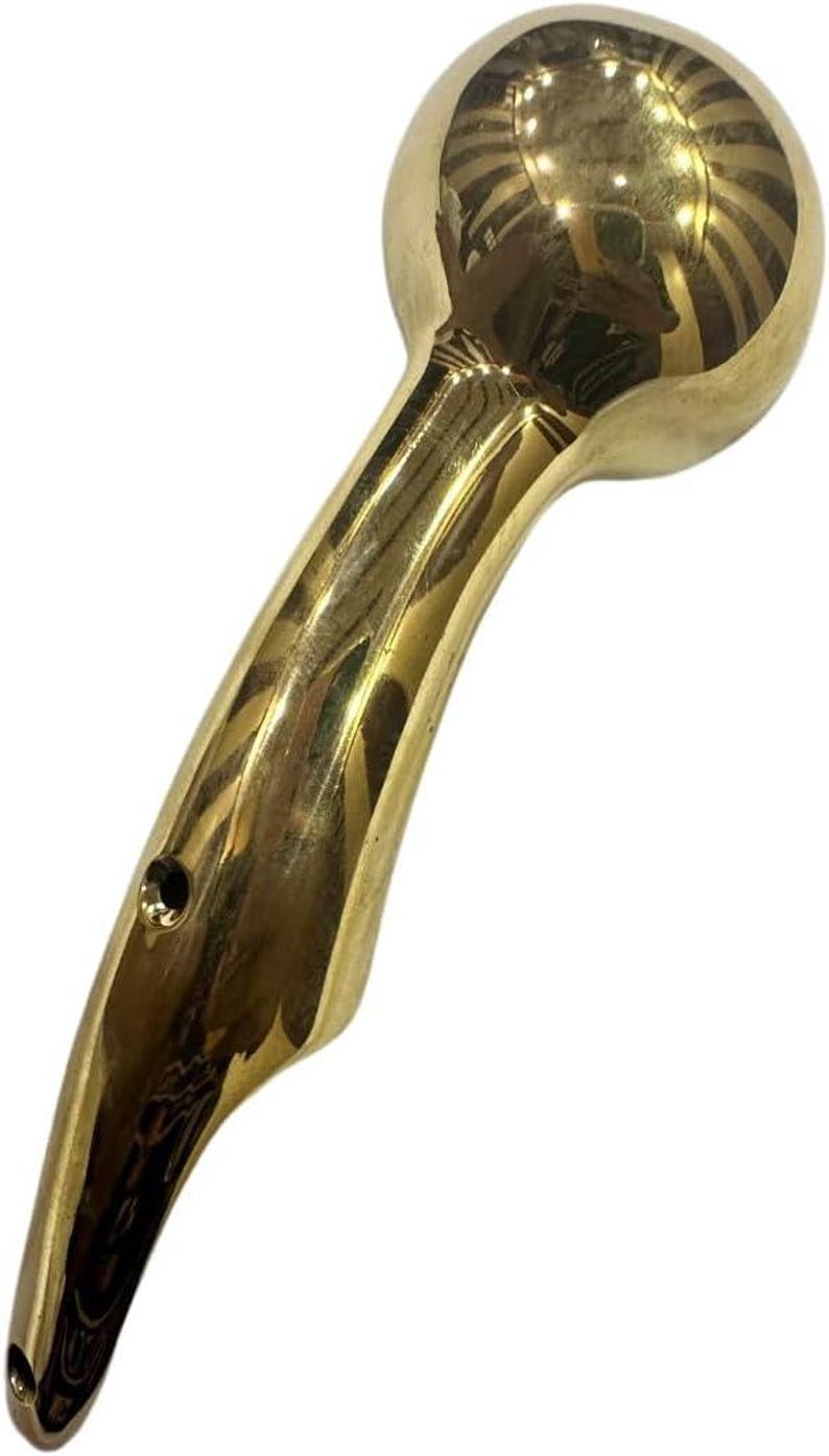 May include: A golden-colored, handheld shower head with a rounded top and curved handle. The shower head has a smooth, reflective surface and a small hole near the handle's base. The design is sleek and modern.