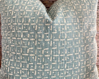 Könnte beinhalten: Ein quadratisches Zierkissen mit geometrischem Muster. Das Kissen hat einen hellblauen Hintergrund mit einem sich wiederholenden Design aus cremefarbenen Quadraten und Linien. Es besteht aus einem strukturierten Stoff.