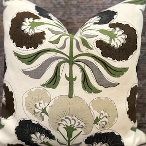 May include: A white cushion with a floral pattern in shades of brown, green, and grey. The flowers are stylised and have a vintage feel.