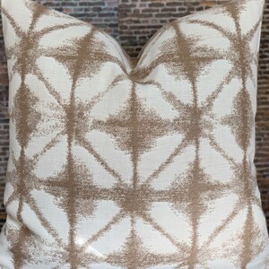 May include: A white throw pillow with a geometric pattern in brown. The pattern is made up of overlapping diamonds and stars.