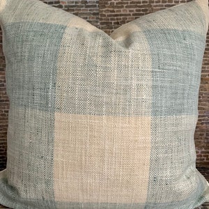 Puede incluir: Una almohada de tiro a cuadros azul y beige con textura tejida.