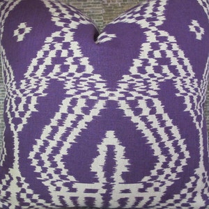 May include: Square decorative pillow with a purple and white geometric pattern. The pillow features a symmetrical design with a textured appearance. The color scheme is a deep purple and off-white, creating a striking contrast.