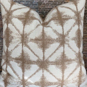 May include: A white throw pillow with a geometric pattern in brown. The pattern is made up of overlapping diamonds and stars.