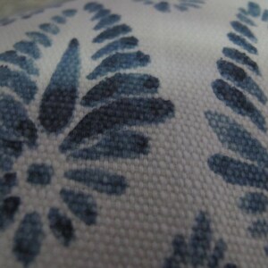 Puede incluir: Primer plano de una tela blanca con un patr&oacute;n repetido de dise&ntilde;os florales azules. El patr&oacute;n presenta hojas y flores estilizadas en varios tonos de azul, creando una apariencia texturizada. La tela tiene una textura tejida.