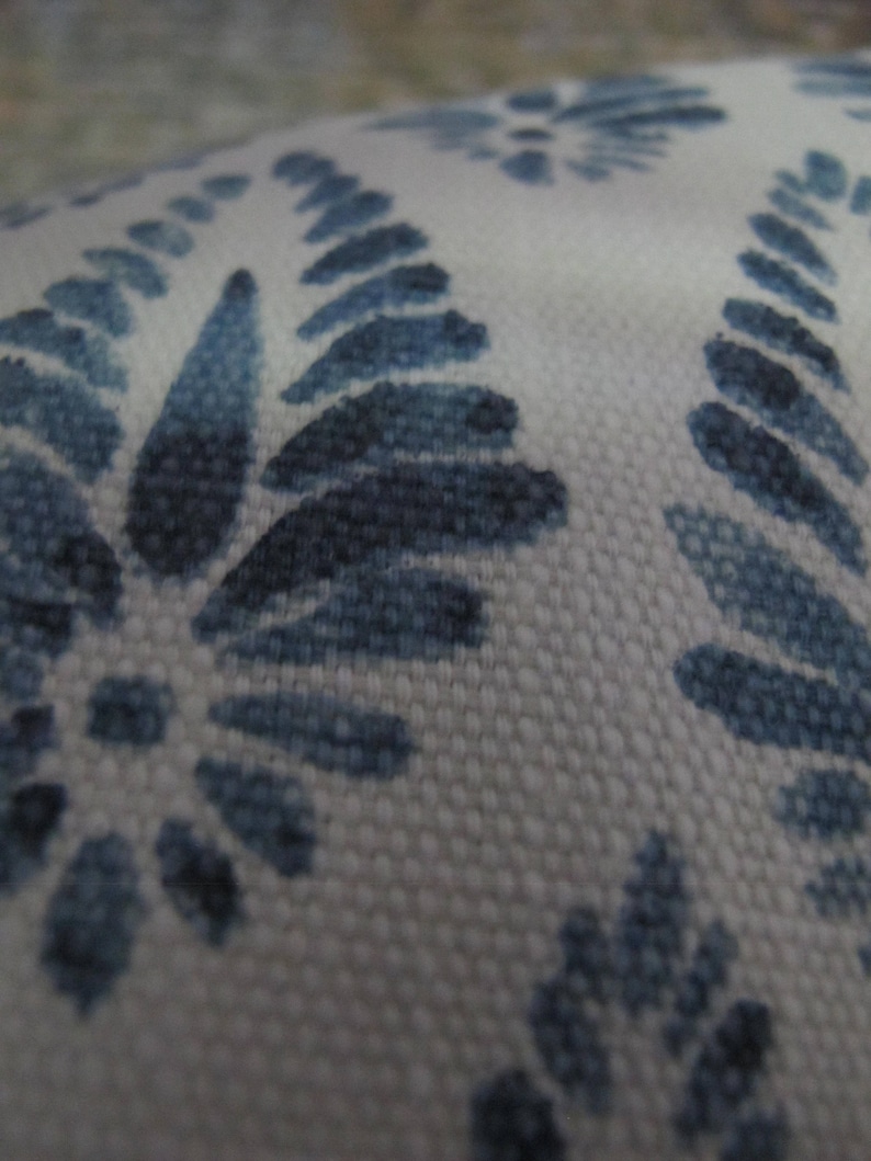 Puede incluir: Primer plano de una tela blanca con un patr&oacute;n repetido de dise&ntilde;os florales azules. El patr&oacute;n presenta hojas y flores estilizadas en varios tonos de azul, creando una apariencia texturizada. La tela tiene una textura tejida.