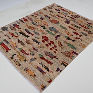 Könnte beinhalten: Ein rechteckiger beiger Teppich mit einem sich wiederholenden Muster aus bunten Fischen. Die Fische sind in verschiedenen Farben, darunter Rot, Orange, Grün und Blau. Der Teppich hat einen Fransenrand.