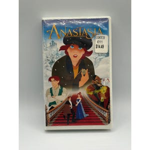 Könnte beinhalten: Eine originalverpackte VHS-Kassette des Animationsfilms Anastasia mit einer zentralen Abbildung der Hauptfigur mit schwarzer Mütze, weiteren Charakteren auf einer roten Treppe und einem Costco-Preisschild in der oberen rechten Ecke.