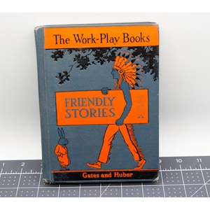 Puede incluir: Libro infantil vintage titulado "The Work-Play Books" con "Friendly Stories" en texto naranja sobre fondo azul. La portada presenta una ilustración de una figura nativa americana que lleva un letrero y un conejo.