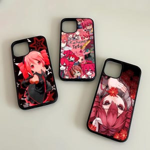 May include: Three black phone cases with anime-style character designs. One case features a red-haired character with star accents, another has a collage of characters, and the third displays a character with red flowers. The cases are on a white surface.