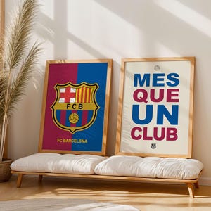 May include: Two framed posters with wooden frames. One features the FC Barcelona logo and text, the other reads "MES QUE UN CLUB." The posters are displayed on a white bench with a neutral background, creating a clean and modern aesthetic.