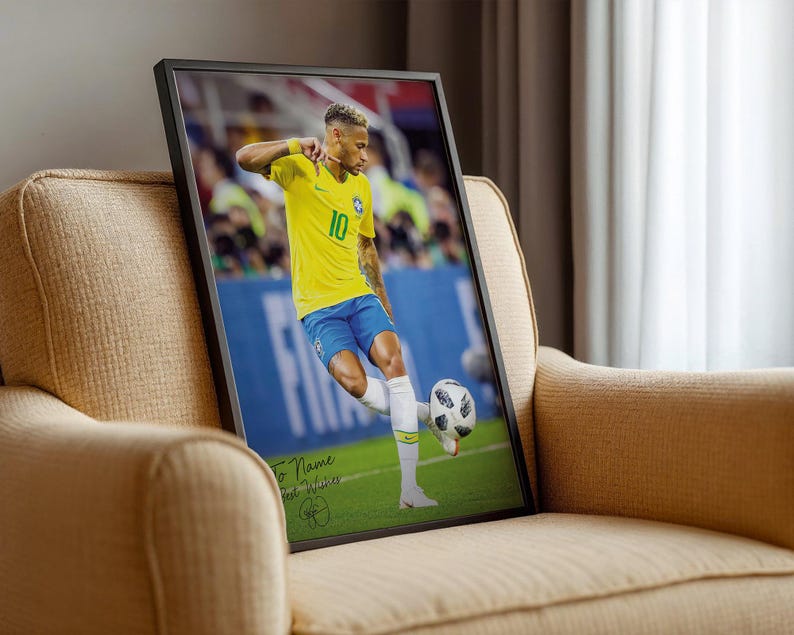 Pode incluir: Impress&atilde;o emoldurada de um jogador de futebol com uma camisa amarela com o n&uacute;mero 10, chutando uma bola de futebol em um campo verde. A impress&atilde;o est&aacute; em uma moldura preta e repousa em uma poltrona bege.
