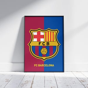 May include: Framed poster featuring the FC Barcelona crest. The design is split vertically, with a burgundy and blue background. The crest is a shield shape with a cross, stripes, and a soccer ball. The text "FC BARCELONA" is at the bottom.