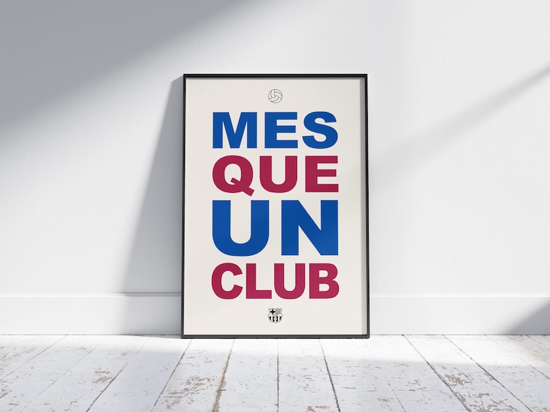 May include: Framed poster with the text "MES QUE UN CLUB" in blue and maroon, with a soccer ball and crest icon. The poster is displayed against a white wall and a wooden floor.