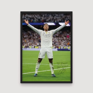 May include: Framed photograph of a soccer player in a white uniform with the Emirates logo, arms raised in celebration on a green field. The image includes the text "To Name Best Wishes" and a signature.