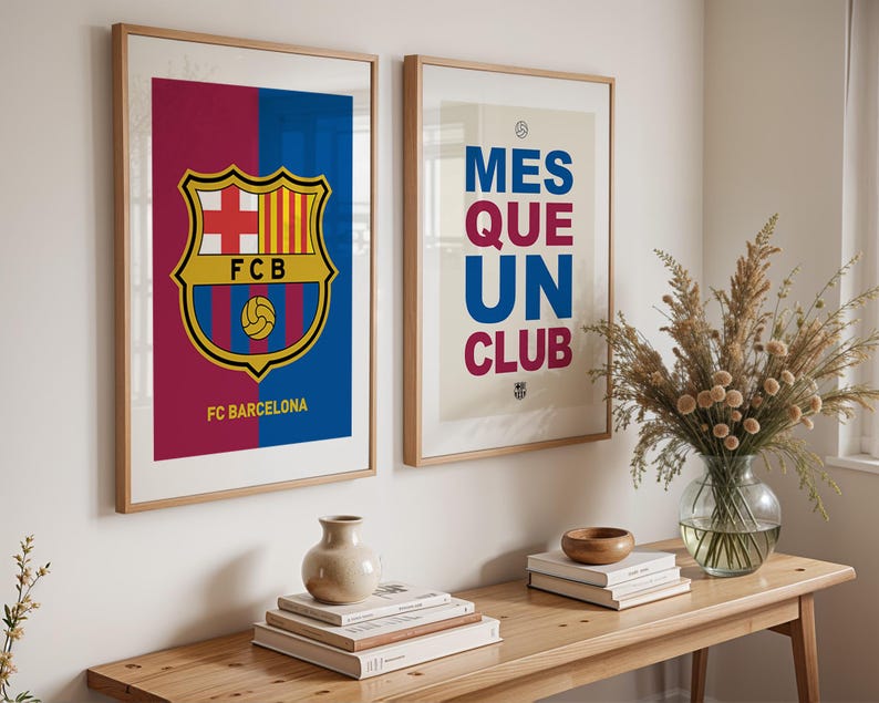 May include: Two framed art prints featuring FC Barcelona branding. One print displays the team's crest with the text "FC Barcelona" below. The other print has the text "MES QUE UN CLUB" in blue and red.