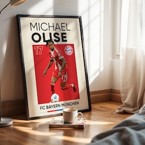 Pode incluir: Um cartaz vertical emoldurado com um gr&aacute;fico do jogador de futebol Michael Olise com o equipamento vermelho do FC Bayern M&uuml;nchen e o n&uacute;mero 17. O design inclui o texto MICHAEL OLISE no topo e FC BAYERN M&Uuml;NCHEN na parte inferior num fundo creme.