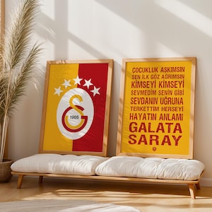 Könnte beinhalten: Zwei gerahmte Poster mit Holzrahmen. Eines zeigt das Galatasaray-Logo in Gelb, Rot und Weiß mit dem Jahr 1905. Das andere Poster hat türkischen Text mit dem Wort "GALATASARAY" in großen Buchstaben.