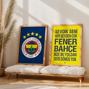 May include: Two framed posters with wooden frames. One features the Fenerbahce logo on a navy blue background. The other has yellow background with text in navy blue. Both are displayed on a white cushioned bench.