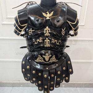Könnte beinhalten: Schwarze römische Lederpanzerung mit goldenen Akzenten, ausgestellt auf einem Holzständer. Die Brustplatte zeigt ein Adleremblem und dekorative goldene Details. Die Rüstung umfasst Schulterpanzer und einen Rock aus Lederstreifen.