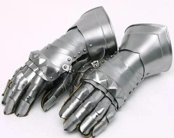 May include: A pair of silver-colored medieval knight gauntlets. The gauntlets are made of metal plates riveted together, with articulated fingers and wrist protection. The text "MEDIEVAL KNIGHT" is in the upper left corner.