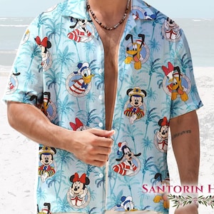 May include: Light blue button-down shirt with a tropical pattern featuring Disney characters like Mickey Mouse, Minnie Mouse, Donald Duck, and Pluto. The shirt has short sleeves and a relaxed fit, perfect for a casual, beachy vibe.