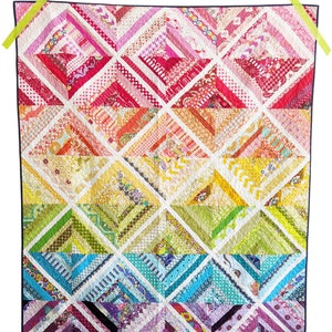 Puede incluir: Una colcha colorida con un patrón de arcoíris. La colcha está hecha de diferentes telas con varios patrones y colores. La colcha está bordeada con una tela azul oscuro.