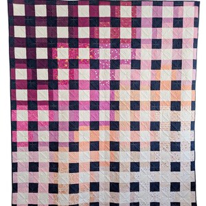 May include: A quilt with a checkered pattern in shades of pink, peach, and white. The squares are outlined in black.