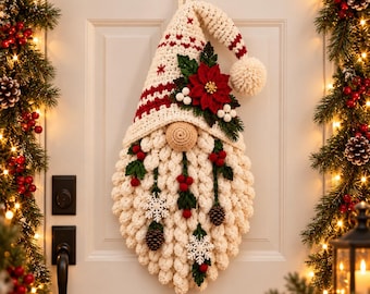 Pode incluir: Um enfeite de parede de gnomo de Natal em crochê com um gorro alto na cor creme com listras vermelhas e um pompom, um nariz grande bege e uma barba espessa na cor creme decorada com bagas vermelhas, folhas verdes, pinhas e flocos brancos.