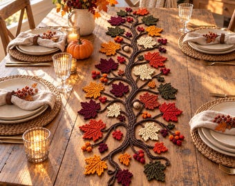 Pode incluir: Um caminho de mesa em crochê com um design central de galho de árvore adornado com várias folhas de bordo em cores de outono, em tons de vermelho, laranja, amarelo e verde, acentuado com pequenos cachos de bagas e bolotas ao longo.
