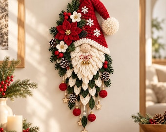 Pode incluir: Uma tapeçaria de crochê em forma de gnomo com gorro vermelho, barba branca e um pompom. A figura é decorada com ramos de pinheiro verdes, poinsétias vermelhas, flores brancas, pinhas, ornamentos vermelhos e estrelas de madeira.