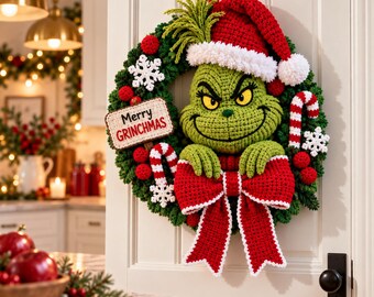 Pode incluir: Uma guirlanda de crochê de um personagem verde com um gorro de Papai Noel vermelho com borda branca, um grande laço vermelho, bengalas doces e flocos de neve brancos. Uma placa retangular exibe o texto Merry GRINCHMAS em letras pretas e vermelhas.