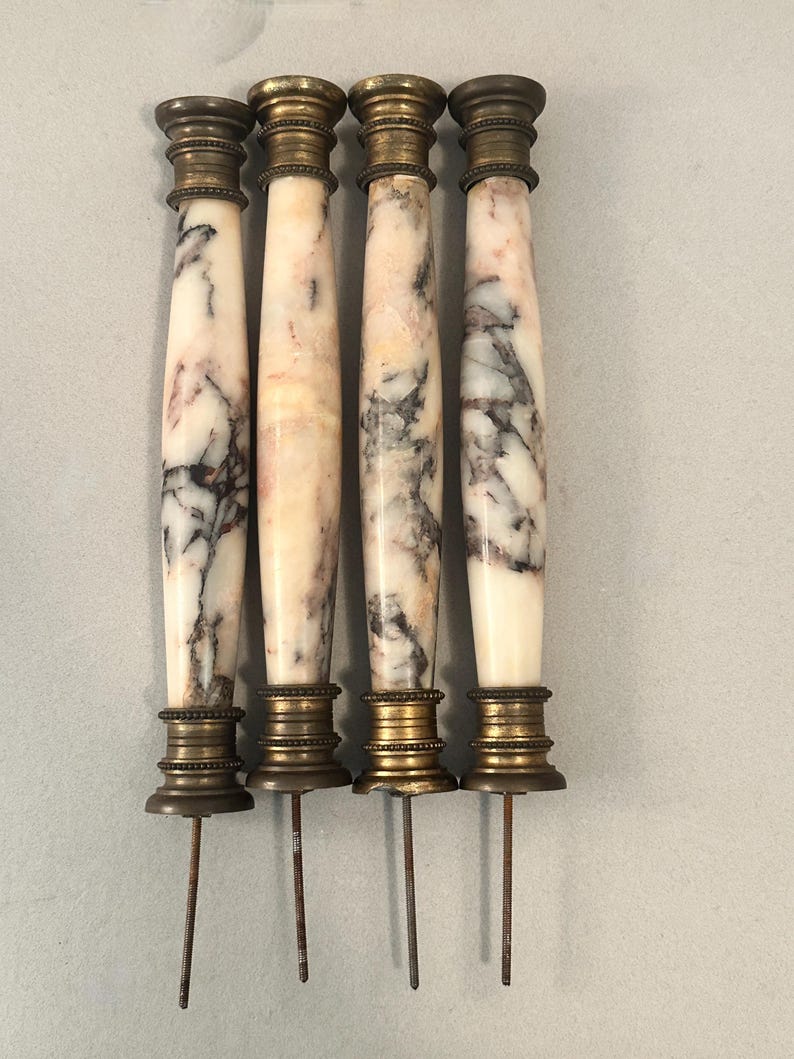 K&ouml;nnte beinhalten: Vier antike Marmorspie&szlig;e mit Messingakzenten. Die Spie&szlig;e haben ein wei&szlig;es und rosa Marmormuster mit dunkelgrauer Maserung. Jeder Spie&szlig; hat eine Ober- und Unterseite aus Messing und einen langen Metallstift.