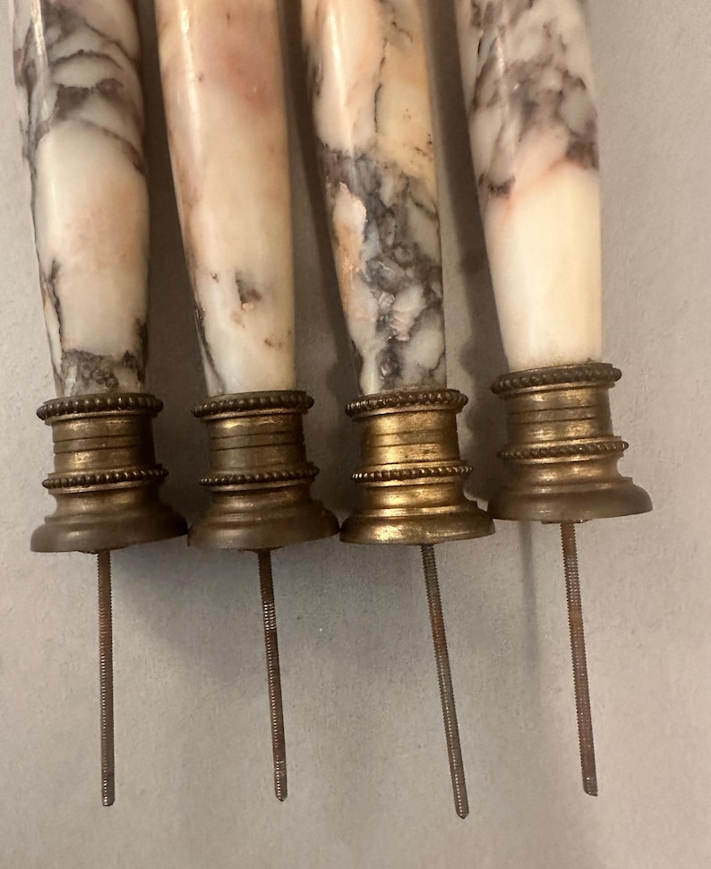 K&ouml;nnte beinhalten: Vier antike Spie&szlig;e aus Marmor und Messing. Die Marmorgriffe haben ein wei&szlig;es und graues Adernmuster. Die Messingbasen sind verziert, und die Spie&szlig;e haben lange, gewindef&ouml;rmige Metallst&auml;be.