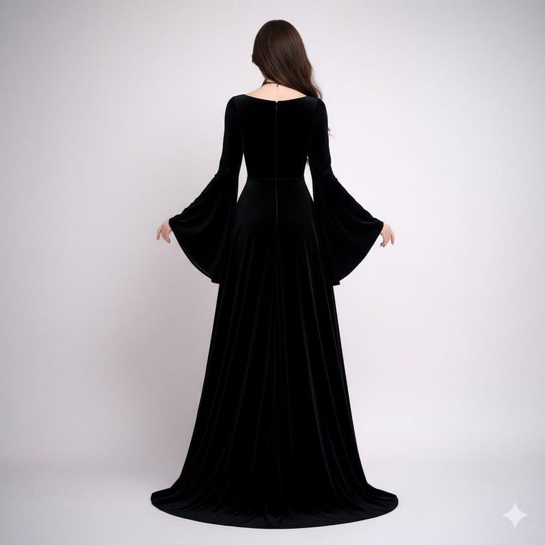 Pode incluir: Vestido longo de veludo preto com decote quadrado e mangas amplas. O vestido tem um corpete justo e uma saia fluida que se arrasta no ch&atilde;o. A parte de tr&aacute;s do vestido &eacute; vis&iacute;vel, com fecho de correr.