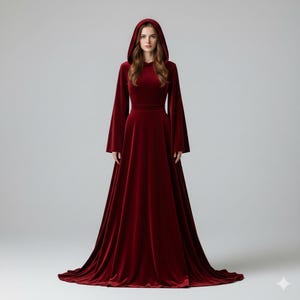 May include: A long, flowing, burgundy velvet gown with a hood. The dress features long, bell sleeves and a fitted bodice that flares into a full skirt. The gown is floor-length and has a slight train.