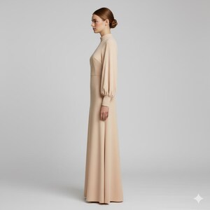 May include: A long, beige dress with a high neckline and long sleeves. The dress has a fitted bodice and a flowing skirt. The sleeves are gathered at the wrist. The dress is made of a smooth, solid fabric and is suitable for formal occasions.