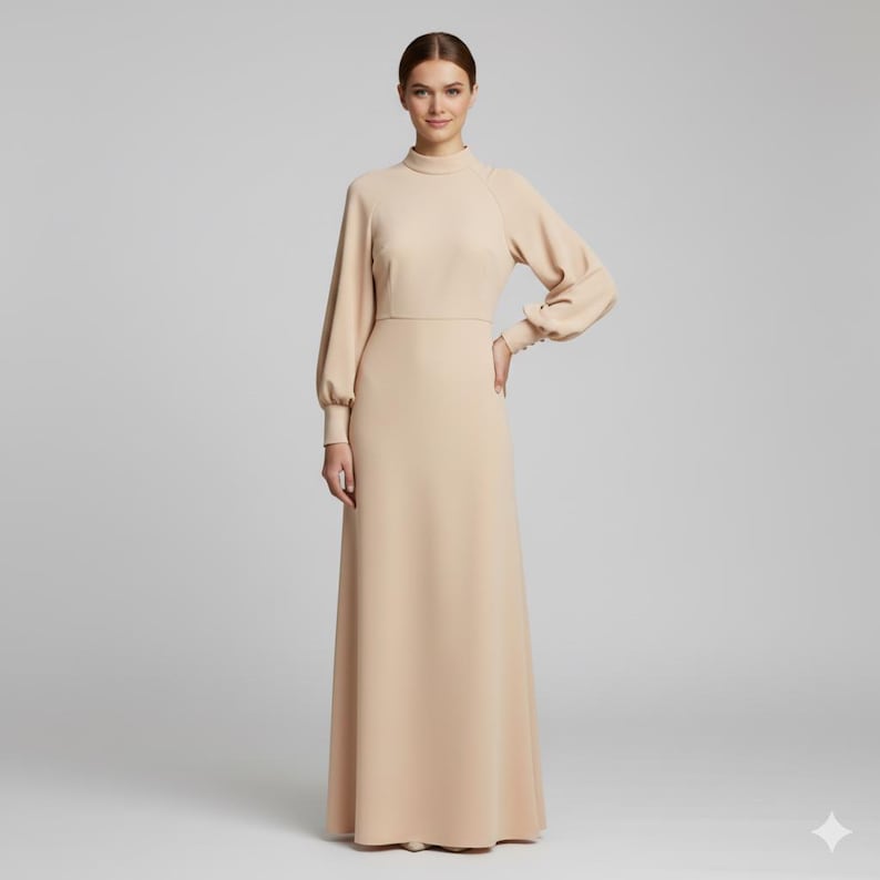 May include: A long, beige dress with a high neckline and long sleeves. The dress has a fitted bodice and a flowing skirt. The sleeves have a slight puff at the shoulder and buttoned cuffs. The dress is made of a smooth, solid fabric.