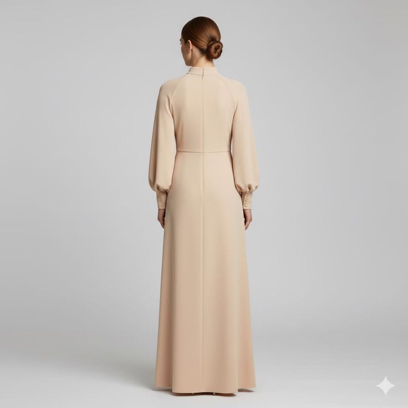 May include: A long, beige dress with a high neckline and long sleeves. The dress features a fitted bodice and a flowing skirt. The sleeves have a slight puff at the shoulder and are fitted at the wrist. The dress is made of a smooth, solid fabric.