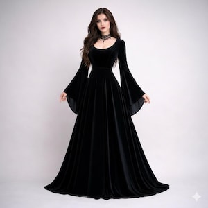 Pode incluir: Um vestido longo de veludo preto com decote redondo e mangas largas e fluidas. O vestido tem um corpete justo e uma saia longa at&eacute; ao ch&atilde;o. Um colar gargantilha preto &eacute; usado ao redor do pesco&ccedil;o.