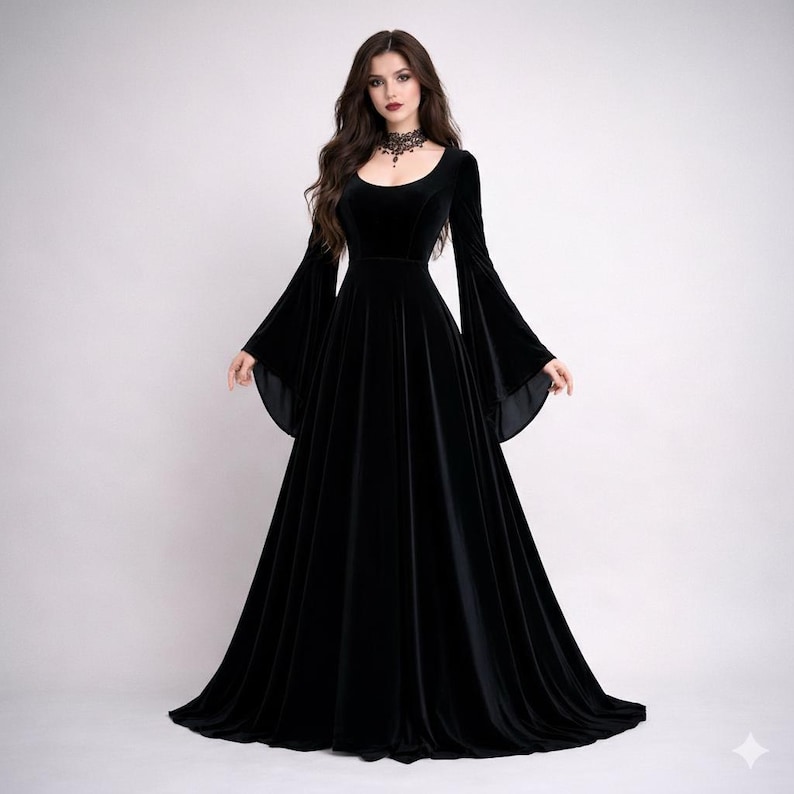 Pode incluir: Um vestido longo de veludo preto com decote redondo e mangas largas e fluidas. O vestido tem um corpete justo e uma saia longa at&eacute; ao ch&atilde;o. Um colar gargantilha preto &eacute; usado ao redor do pesco&ccedil;o.
