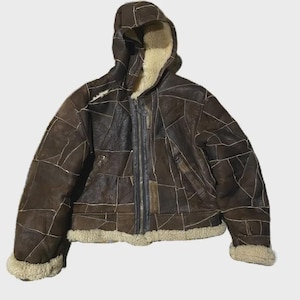 以下が含まれることがあります： パッチワークデザインとフードが付いた茶色のレザージャケット。 ジャケットは、フルジッパー開閉、クリーム色のシアリング裏地、袖口と裾のシアリングトリムが特徴です。 スタイリッシュなアウターウェアです。